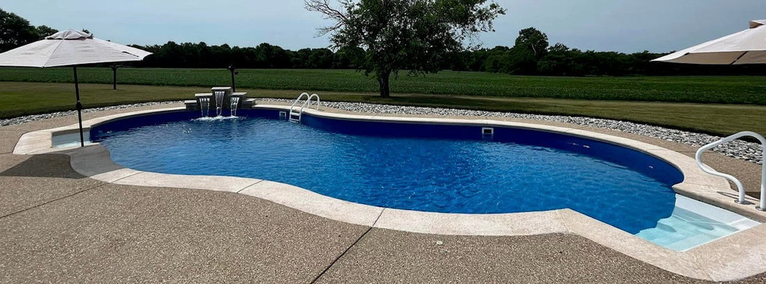 Custom in-ground pool installation with concrete patio and water feature in St. Louis Missouri backyard