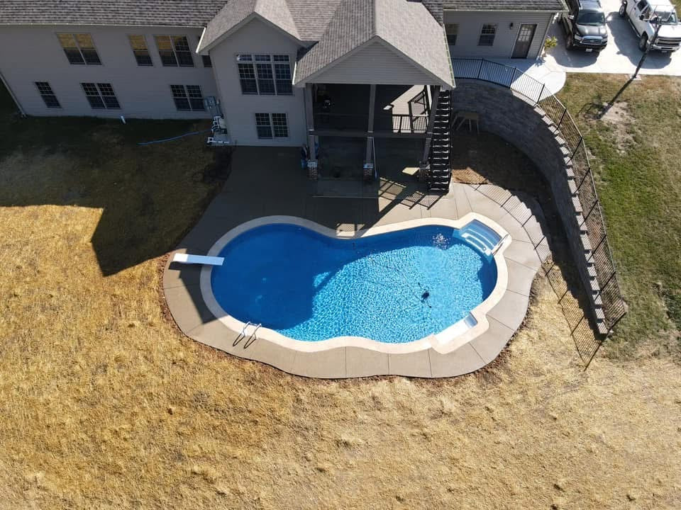 Aerial view of a swimming pool in a backyard with a house in the background.