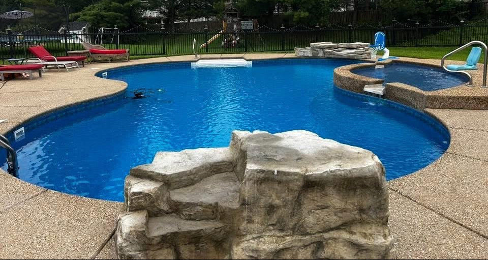In-ground swimming pool with smooth blue water and concrete deck overlooking open landscape in St. Louis area