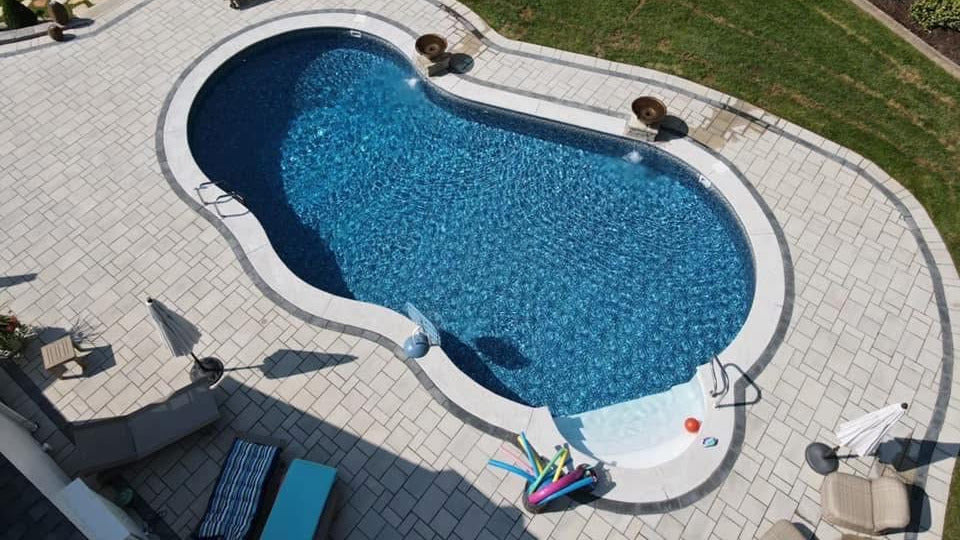 Freeform pool installation with paver patio and landscaping in St. Louis County Missouri backyard