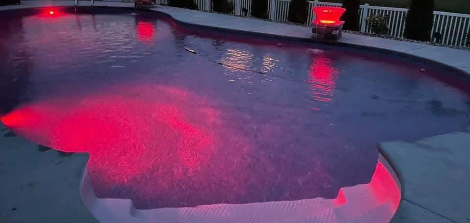 custom in-ground pool with ambiance lighting and waterfall